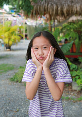 Portrait of happy Asian girl child touching her chin with funny mouth while stay in garden. - 761951501