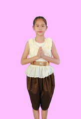 Tidy Asian girl child in traditional Thai dress with Pay respect, Sawasdee symbol, Welcome expression on pink background, front view and clipping path. - 761952177