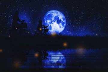 Mother and son riding a bikes full moon and grassland and calm river at nightscape