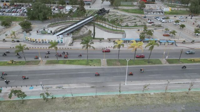 Vista a&eacute;rea de un grupo de motociclistas corriendo y haciendo trucos y acrobacias. Muchas motocicletas en avenida principal. En Aguascalientes, Av. G&oacute;mez Mor&iacute;n. Junto a Plaza de las Tres Centurias.