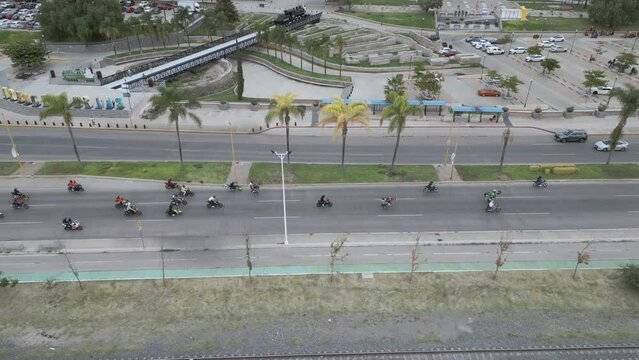 Vista a&eacute;rea de un grupo de motociclistas corriendo y haciendo trucos y acrobacias. Muchas motocicletas en avenida principal. En Aguascalientes, Av. G&oacute;mez Mor&iacute;n. Junto a Plaza de las Tres Centurias.