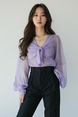 Portrait of a pretty young woman super model of Korean ethnicity donning a lavender chiffon blouse with bell sleeves, paired with high-waisted black trousers and pointed-toe flats