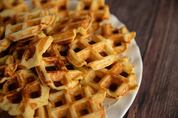 Waffles on a plate on a wooden background, close-up. 