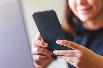 Closeup image of a young woman using smart phone and laptop computer