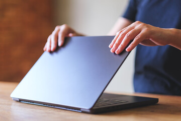 A woman opening or closing laptop computer, getting ready for work