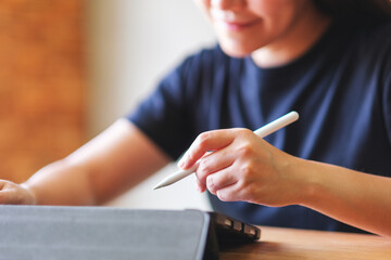 Closeup of a young woman using stylus pen technology for working and writing on digital tablet...