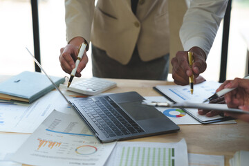 Group of business people meeting, discussion, brainstorming, pointing at graphs and charts to analyze market data, calculating balance sheets, accounts, net profits to plan company sales strategies.