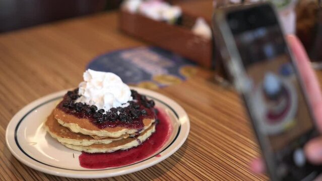 Food Blogger Taking Picture Of Vegan pancakes For Breakfast with blue berries Using Smartphone