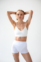 Fototapeta na wymiar Blonde girl posing on a white background in a top and leggings