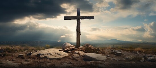 Cross atop rocky hill under cloudy sky