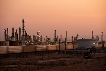 A train passes by an oil refinery at sunset in Bakersfield, California, USA.