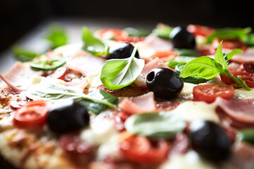 Pizza with ham, mozzarella cheese, cherry tomatoes, green and jalapeno pepper, black olives and fresh basil. Dark background. Close up.	