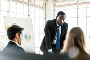 African businessman presents and listens to opinions at a business group meeting, Discussion about last year's review and a new business plan in the office. Businesspeople of various nationalities. - 762032129