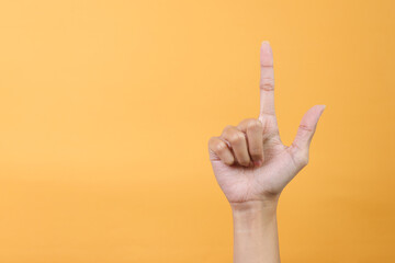 Woman hand pointing upwards isolated on yellow background