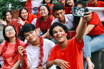 Multi-ethnic group of friends taking a selfie outdoors. Young football supporters having fun on...