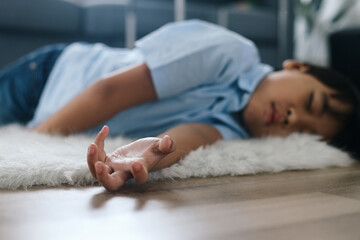 Little boy lying on the floor at home. Healthcare and medical concept.