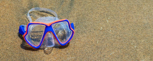 Banner con visor, goggle azul con anaranjado sobre arena de playa