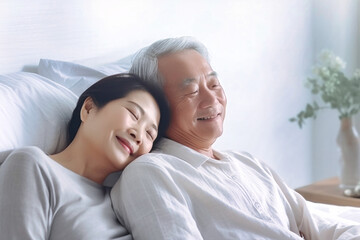 An elderly Asian man and woman are peacefully resting together on a bed