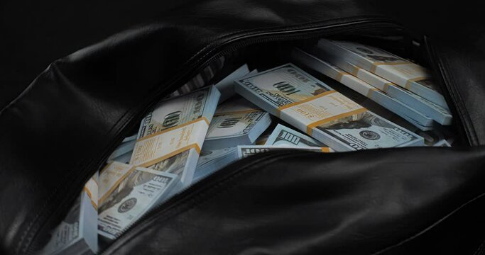 A large bag on a black background filled with money and dollars. Bag with money in dollars for a bribe. The concept of corruption, bribes, theft of money from the city budget.