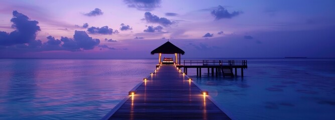 A long wooden pier with lights leads to an overwater gazebo at dusk. - obrazy, fototapety, plakaty