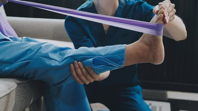 Asian female physiotherapist helping senior older woman stretching hamstring, Rehabilitation physiotherapy, elderly. Causes knee pain, swelling, redness, stiffness in knee, clunking noise in knee.