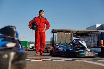 Go-kart driver walking to car before race at starting line on motor racing track