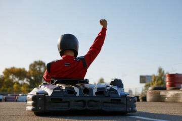 Happy go-cart driver raising hand up rejoicing and celebrating win