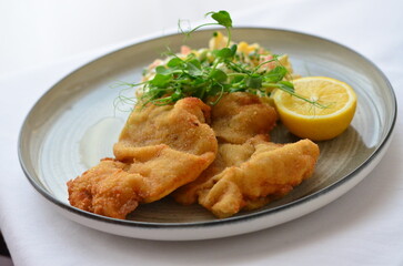 Wiener schnitzel with salad on a restaurant table.