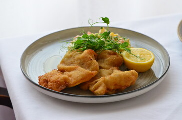 Wiener schnitzel with salad on a restaurant table.