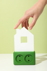 Green electrical outlet with white decorative house