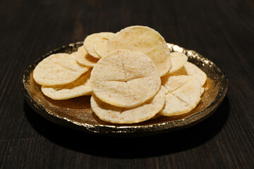 Liturgical bread on golden plate on dark wooden background, close up