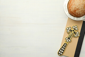 Bread and cross on book on white background, space for text