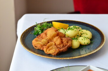 Schnitzel with potatoes on a plate in a restaurant.