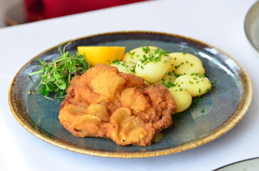Schnitzel with potatoes on a plate in a restaurant.