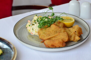 Wiener schnitzel with salad on a restaurant table.
