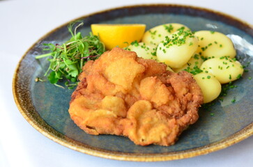 Schnitzel with potatoes on a plate in a restaurant.