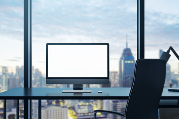 Modern office interior with empty white computer monitor on desk and panoramic windows with beautiful city view and daylight. Mock up. Workplace concept. 3D Rendering.