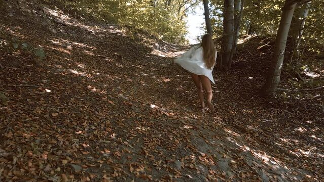 Dreamy, free-spirited girl running through an autumn forest.