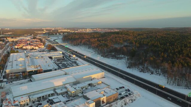 Cars Driving Through The Asphalt Road Along The Forest And Buildings During Winter In Dabrowa, Gdynia. - aerial shot