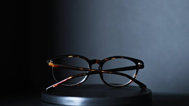 brown and green tortoiseshell round prescription glasses rotating 360 degrees against a black background