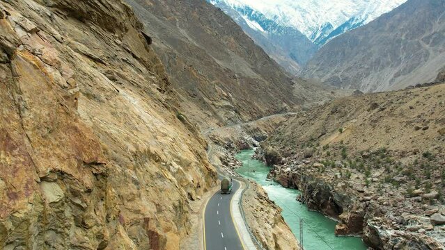 Rear drone view of truck driving through JSR Road by the cliff of mountains in Skardu, Pakistan. Mountains at background.