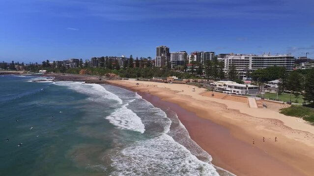 Aerial reveal of surf sand and beach goers enjoying a sunny dat at North Wollongong Beach