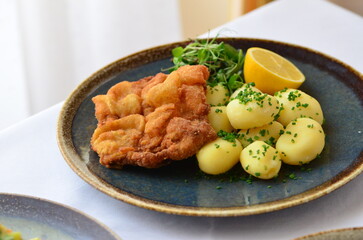 Schnitzel with potatoes on a plate in a restaurant.