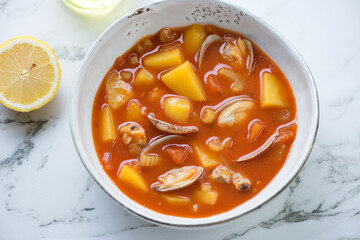 Bowl of manhattan chowder with vongole clams on a white marble background, horizontal shot