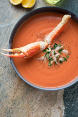 Plate of bisque served with a boiled crab claw, above view on a beige granite background, vertical shot, middle close-up