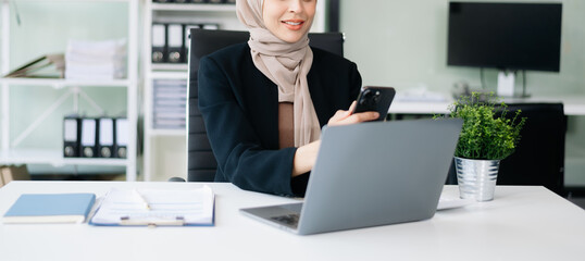 Young Muslim woman working with laptop and tablet