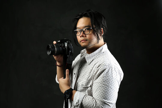 portrait of a photographer with his digital camera on a dark background