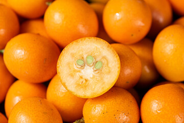 closeup of ripe cumquat or kumquat fruit with half background.