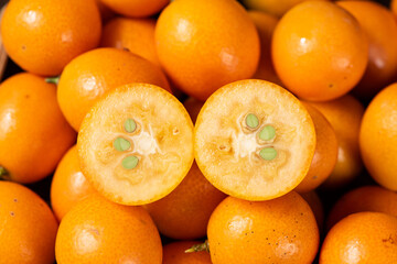 closeup of ripe cumquat or kumquat fruit with half background.