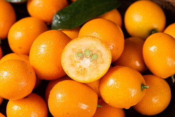 closeup of ripe cumquat or kumquat fruit with half background.